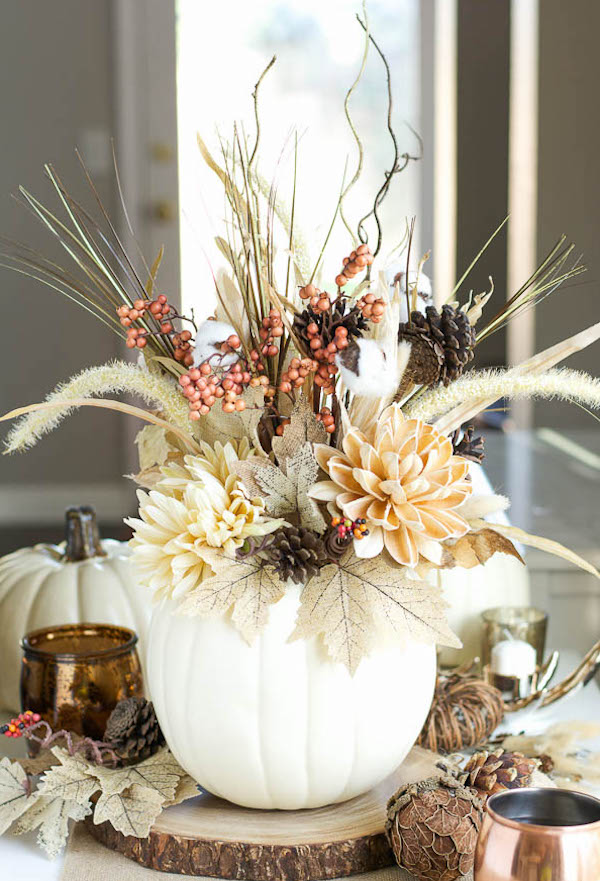 White faux pumpkin vase filled with fall flowers, dried grasses, pinecones, and autumn foliage for DIY Thanksgiving décor.