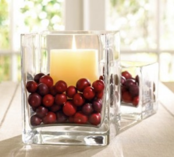 Glass hurricane candle surrounded by fresh cranberries for an elegant DIY Thanksgiving centerpiece.