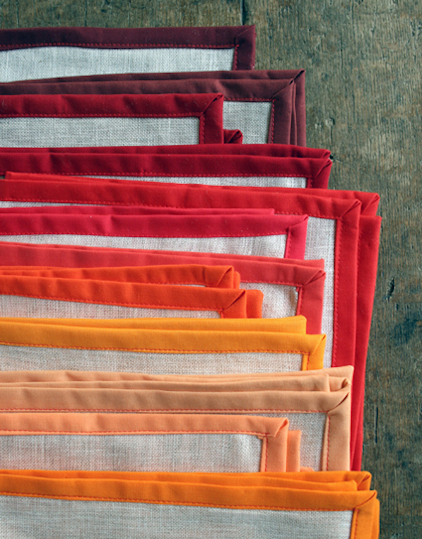 Stack of handmade linen napkins in warm fall colors for a DIY Thanksgiving table setting.
