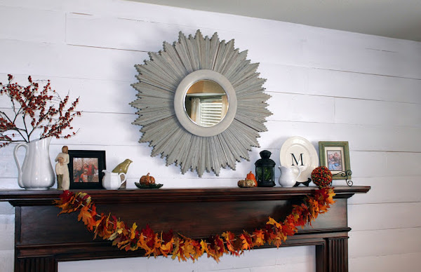 DIY fall leaf garland made with colorful fabric leaves draped across a fireplace mantel for Thanksgiving décor.
