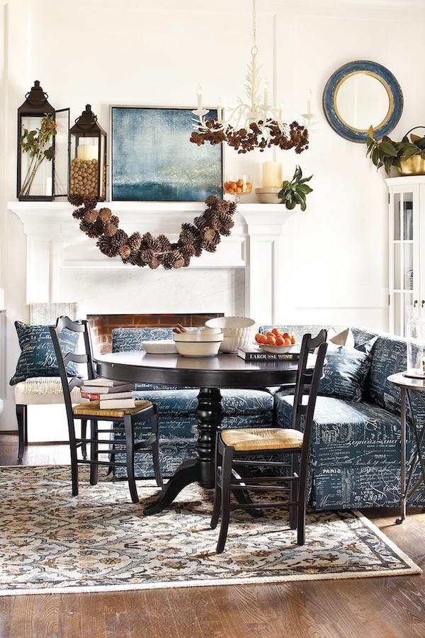 DIY pinecone garland draped across a fireplace mantel in a cozy fall living room decorated for Thanksgiving.