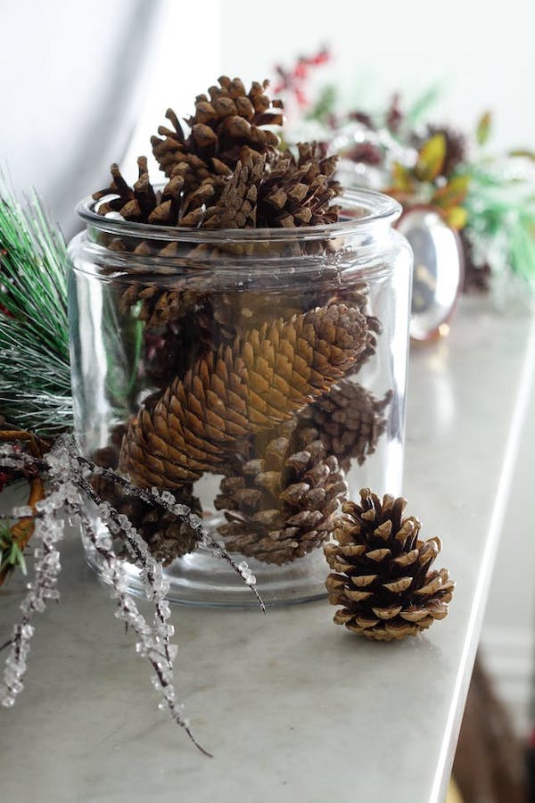 DIY scented pinecones displayed in a glass jar as natural fall and Thanksgiving home décor.