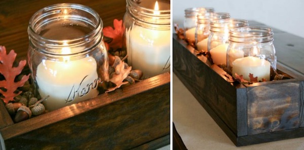Rustic wooden box centerpiece with mason jars, pillar candles, acorns, and fall leaves for a DIY Thanksgiving table.