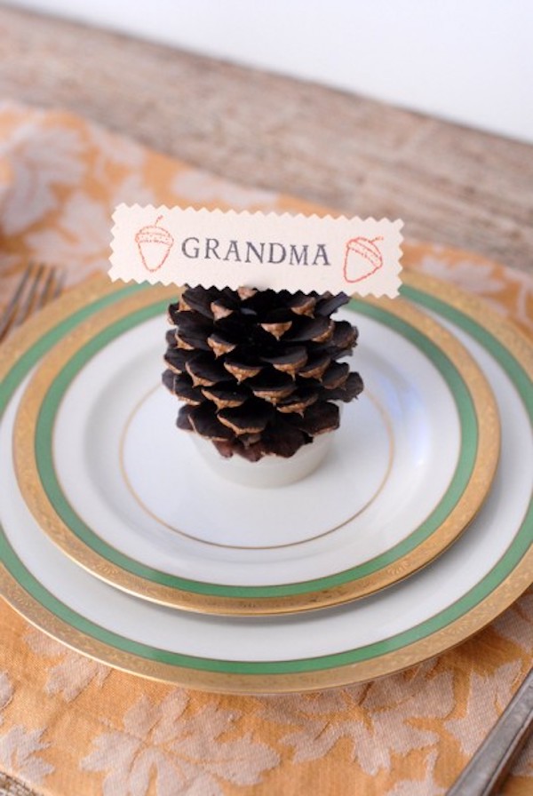DIY pinecone firestarter place card displayed on a Thanksgiving dinner plate with a personalized name tag.