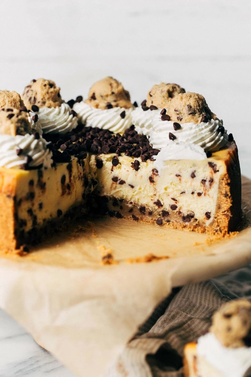 Chocolate chip cookie dough cheesecake with chocolate chip graham cracker crust, creamy vanilla filling mixed with mini chocolate chips, all baked on a layer of soft cookie dough.