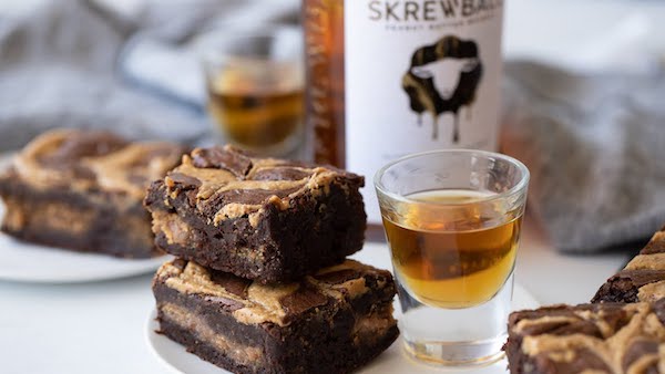 Fudgy peanut butter whiskey brownies with a creamy peanut butter filling and swirled peanut butter topping.