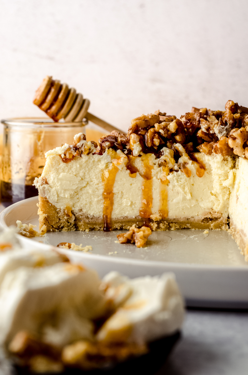 Creamy goat cheese cheesecake featuring a blend of cream cheese and goat cheese cheesecake with a buttery shortbread walnut crust and sticky honey-walnut topping.