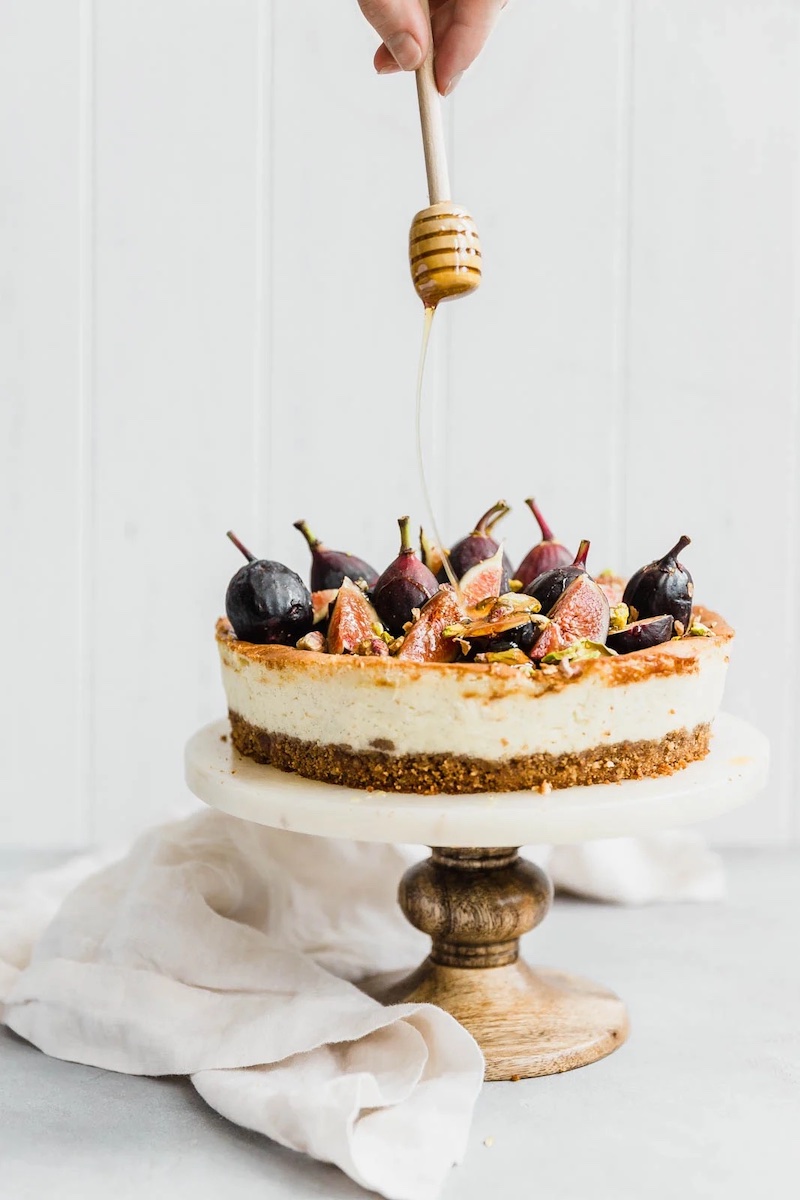 Classic vanilla bean cheesecake with a walnut-graham crust topped with fresh figs, chopped pistachios, and a drizzle of honey.
