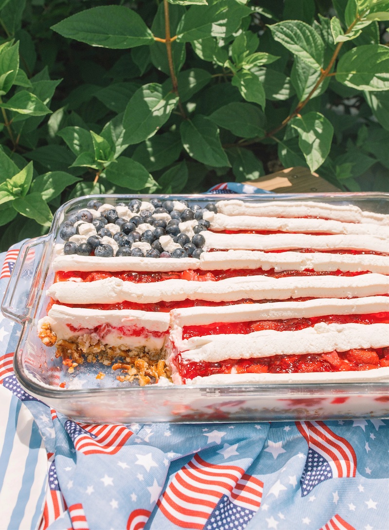 American Flag Strawberry Pretzel Salad with a buttery pretzel crust, creamy cheesecake filling, strawberry Jell-O, whipped topping, and fresh blueberries arranged in a patriotic flag design for the Fourth of July.