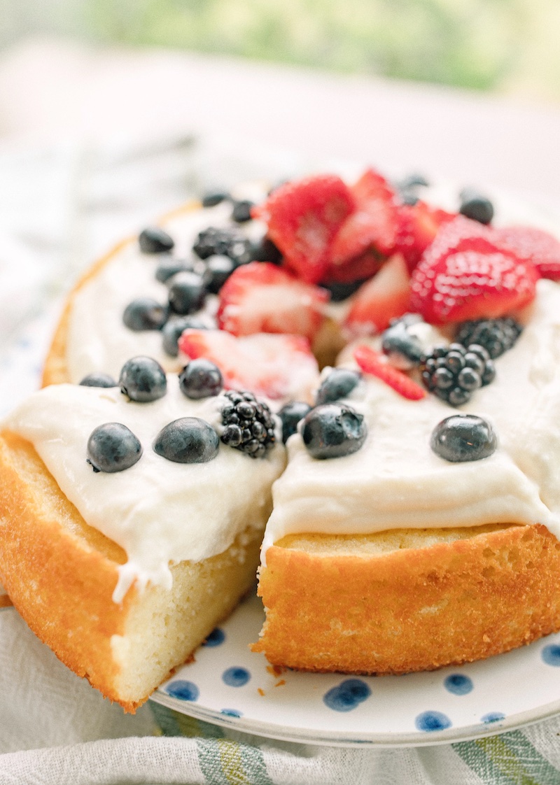 Fresh lemon olive oil cake topped with whipped cream cheese frosting, strawberries, blueberries, and blackberries for an elegant summer dessert perfect for Memorial Day and the Fourth of July.