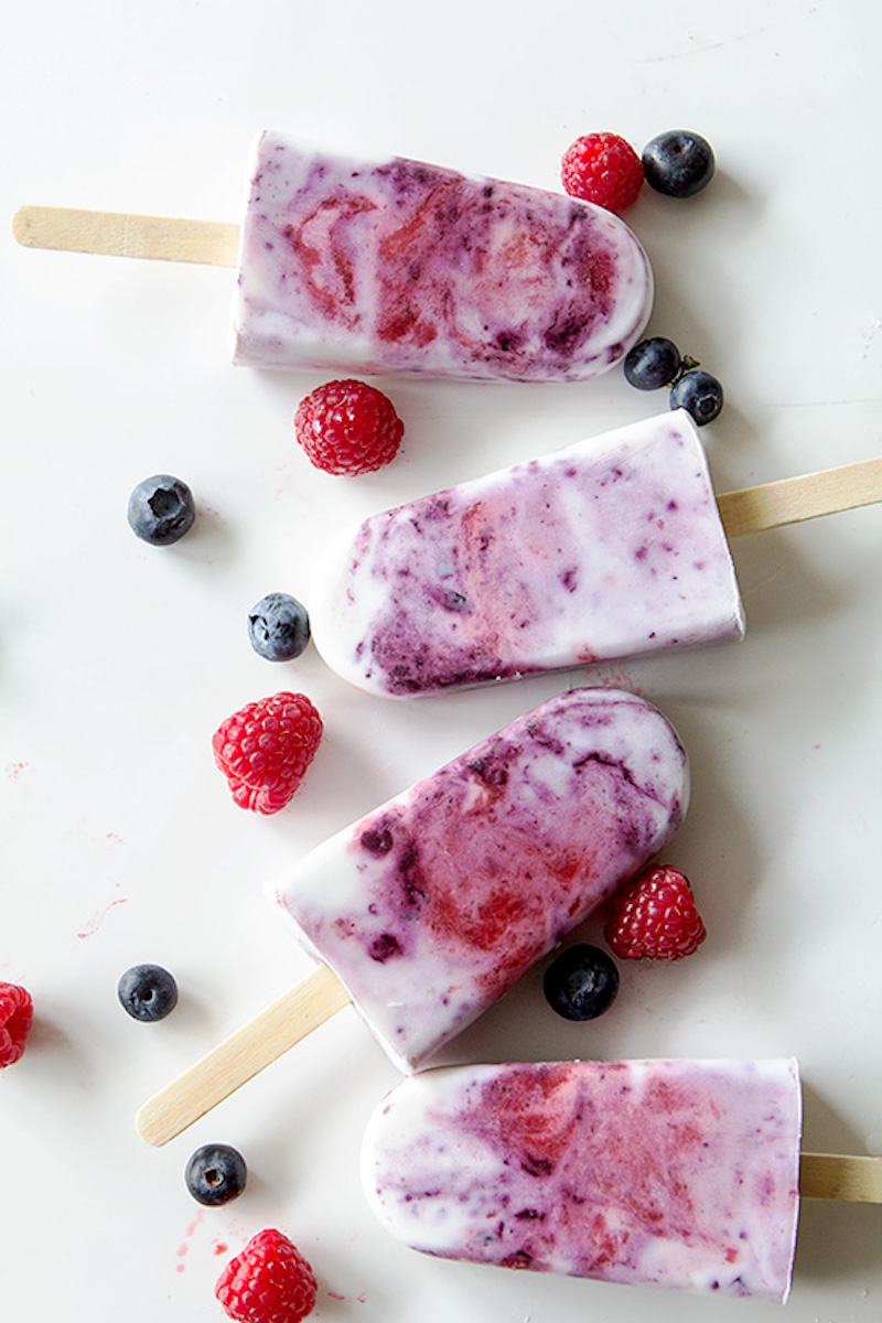 Creamy mixed berry swirl popsicles made with Greek yogurt, mascarpone, strawberries, and blueberries for a refreshing summer dessert.