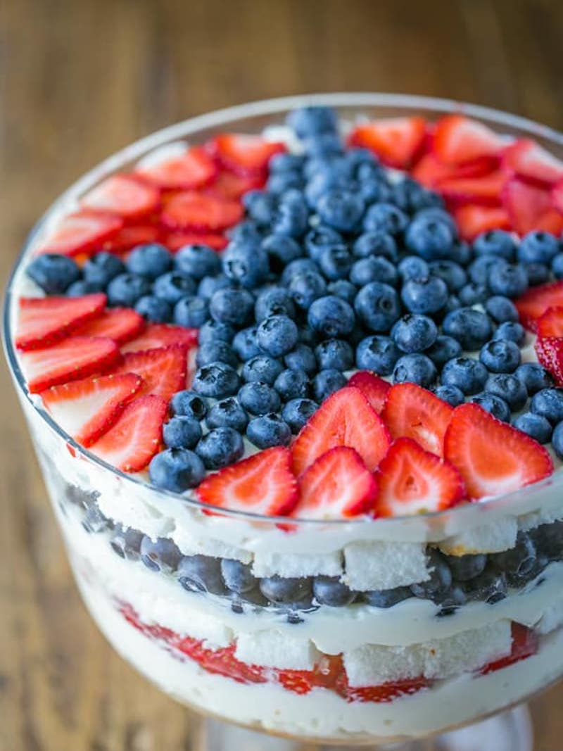 No-bake strawberry blueberry trifle layered with angel food cake, fluffy cream cheese filling, fresh strawberries, and blueberries in a glass trifle bowl.