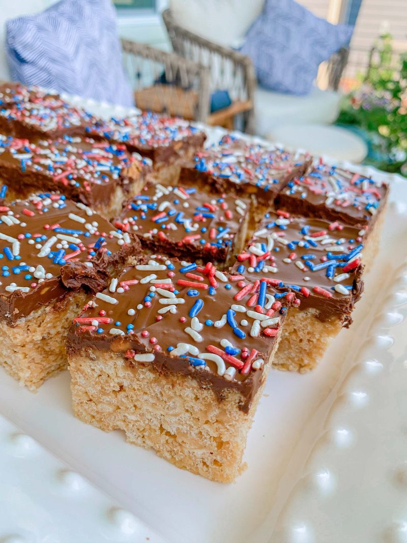 Patriotic Scotcheroos topped with a chocolate and butterscotch layer and red, white, and blue sprinkles for an easy no-bake Fourth of July dessert.