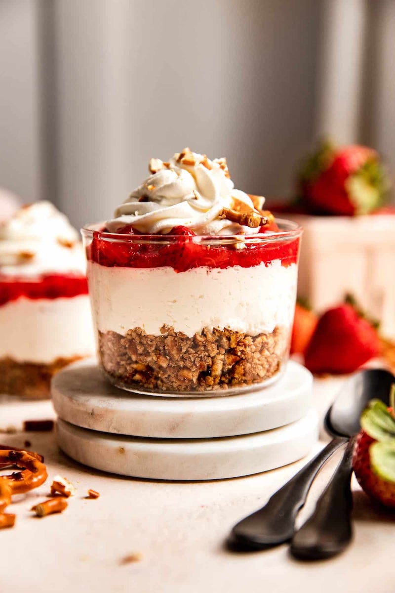 Layered strawberry pretzel salad parfait with a buttery pretzel crust, creamy cheesecake filling, homemade strawberry topping, whipped cream, and crunchy pretzel pieces for an easy summer dessert.