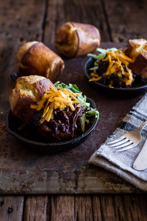 Two plates of BBQ beer pulled chicken with cheddar corn popovers on the side.
