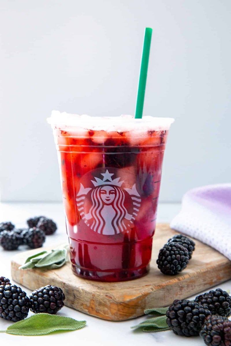 A Starbucks copycat Blackberry Sage Refresher served over ice with freeze-dried blackberries and fresh sage.