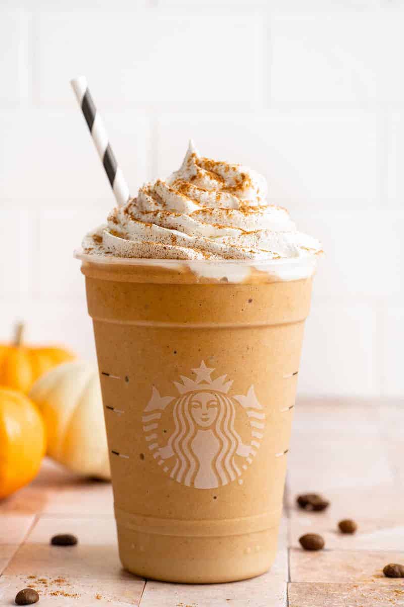 Starbucks Pumpkin Spice Frappuccino topped with whipped cream and pumpkin pie spice in a clear glass.