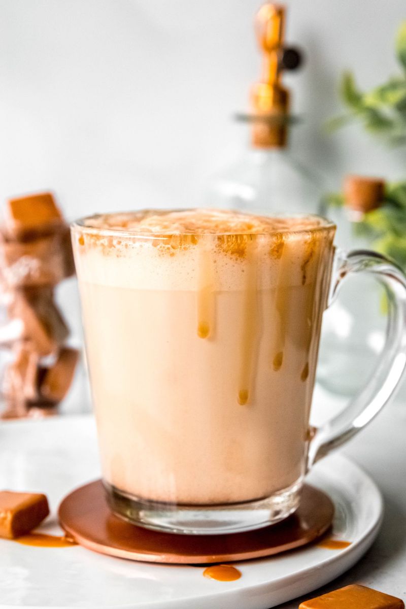 Homemade Starbucks caramel latte in a mug topped with creamy milk foam and finished with a drizzle of caramel sauce.