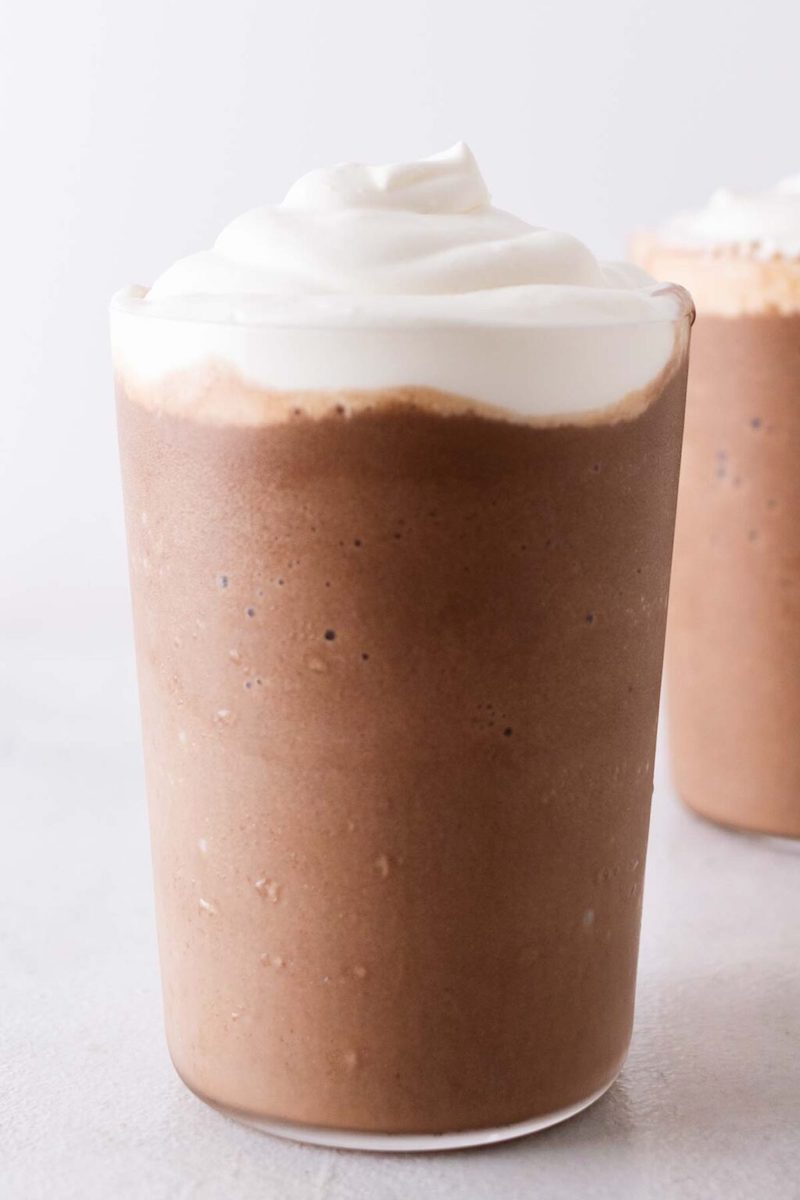 Starbucks Mocha Frappuccino topped with vanilla whipped cream in a clear glass cup.