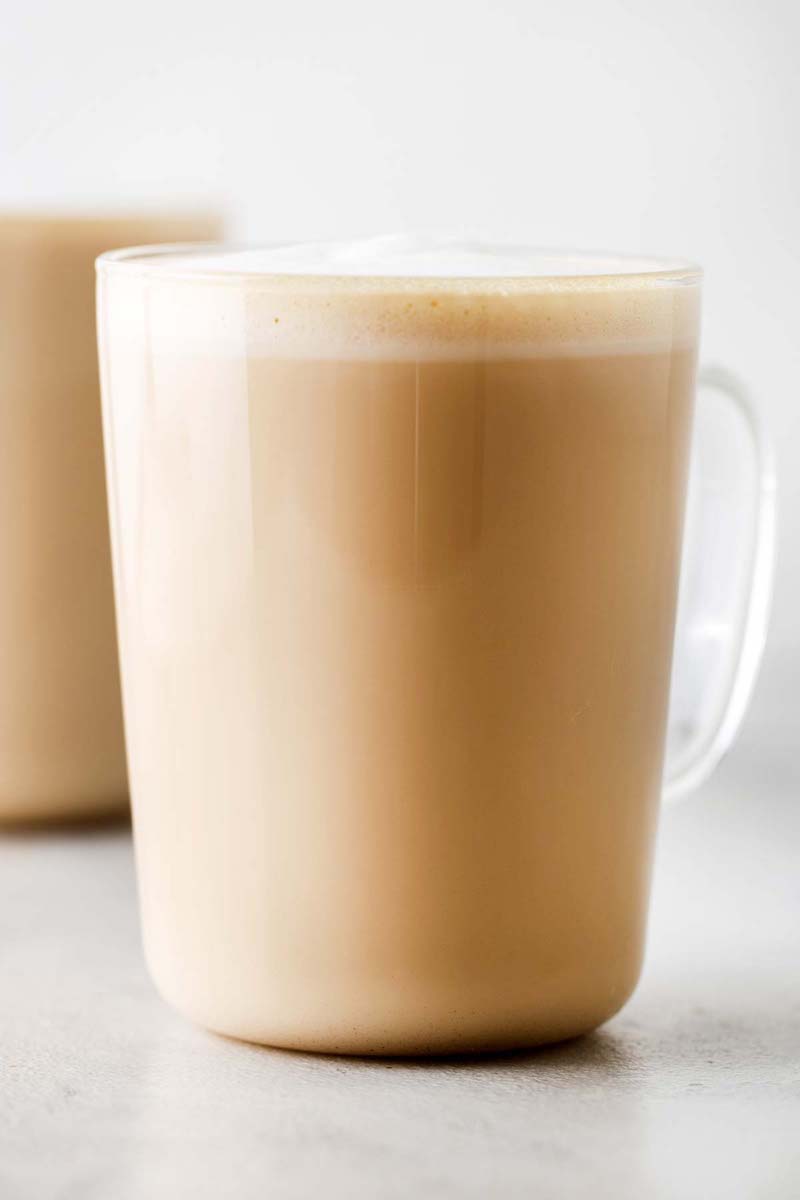 Homemade Starbucks vanilla latte in a clear glass mug with creamy steamed milk and a layer of velvety milk foam on top.