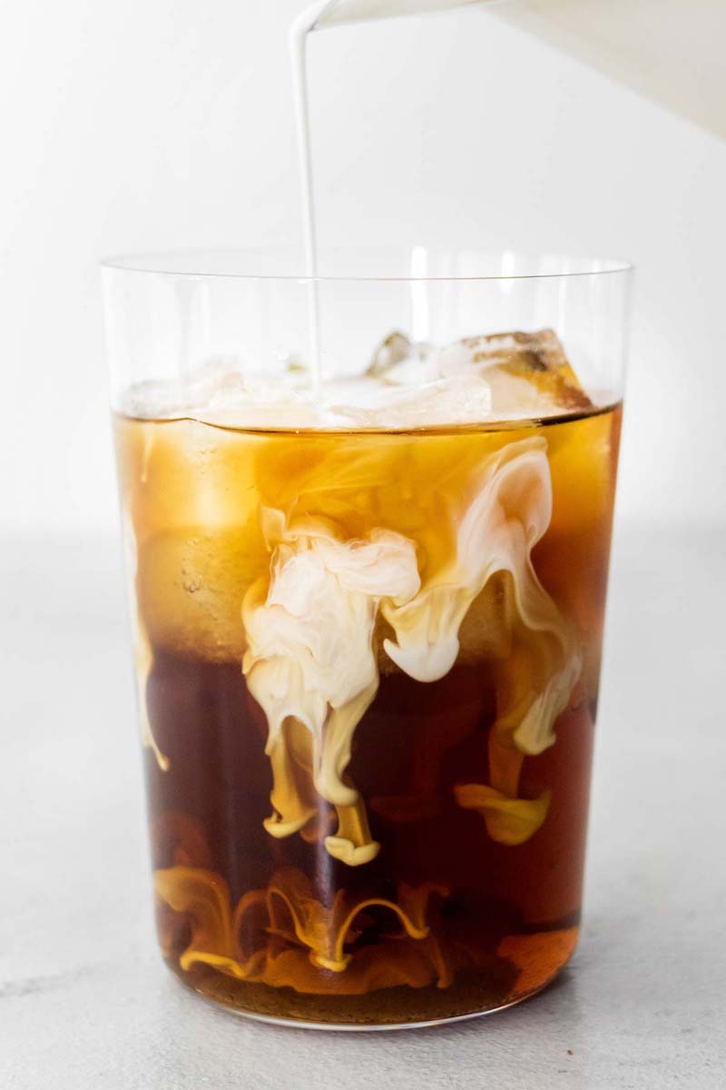 Cream being poured into a Starbucks copycat vanilla sweet cream cold brew over ice.
