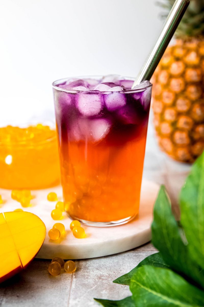 A Starbucks copycat Tropical Butterfly Refresher with vibrant blue butterfly pea tea layered over a tropical fruit refresher and mango popping boba.