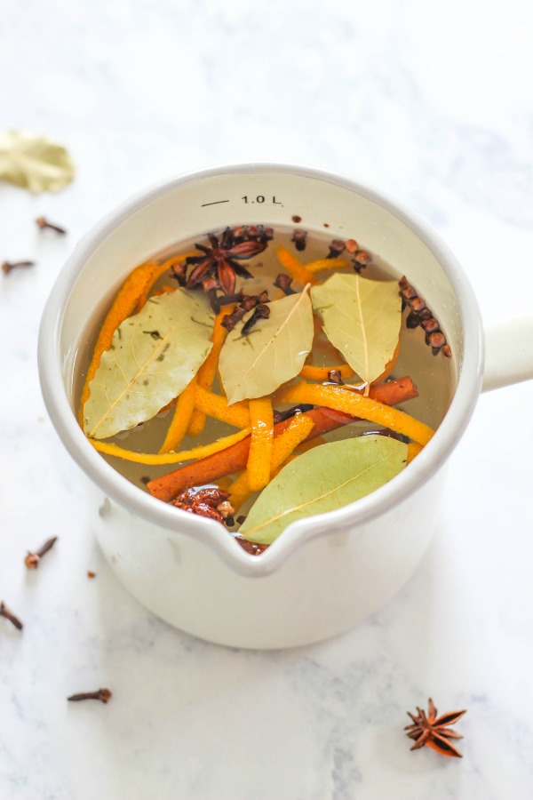 A white ceramic pot containing bay leaves and licorice stovetop potpourri.