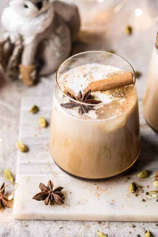 A glass of vanilla chai tea white russian garnished with star anise and cinnamon stick.