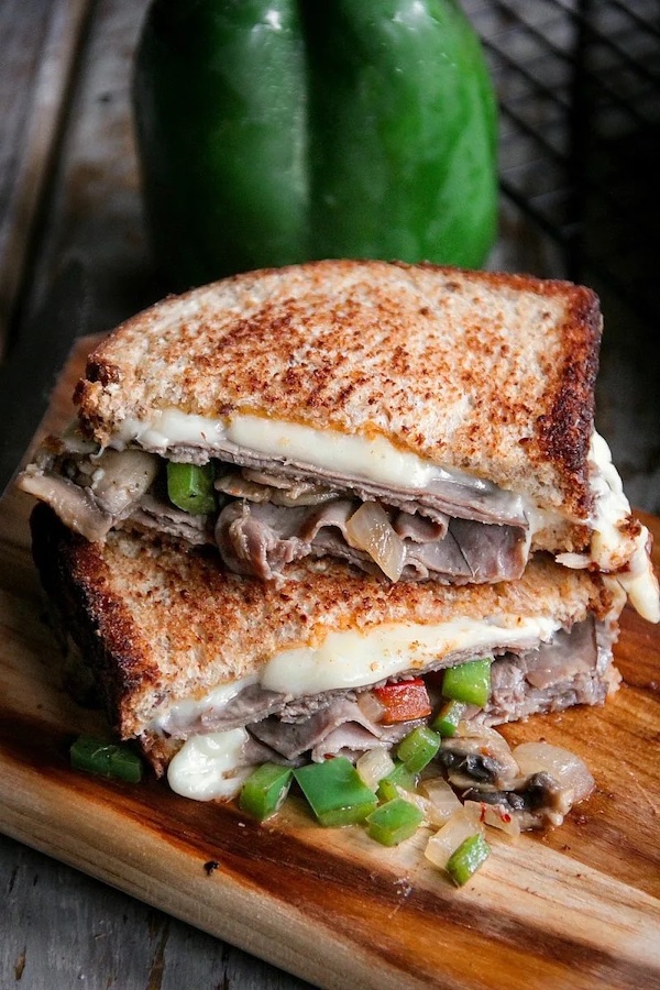 Roast beef grilled cheese sandwich with provolone cheese, sautéed onions, bell peppers, mushrooms, and toasted bread.