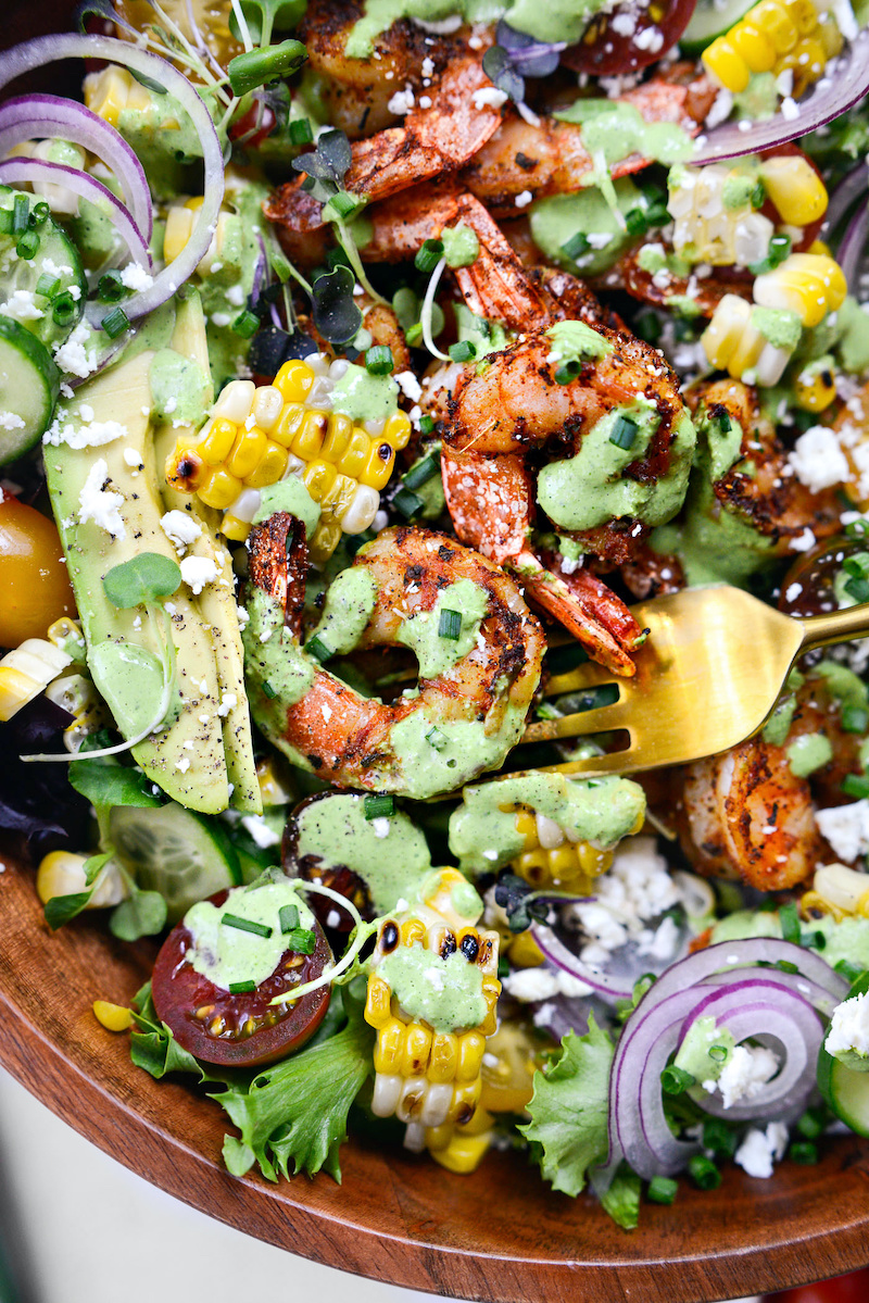 Blackened shrimp salad with grilled corn, avocado, cucumber, cherry tomatoes, red onion, feta cheese, mixed greens, and creamy green goddess dressing.
