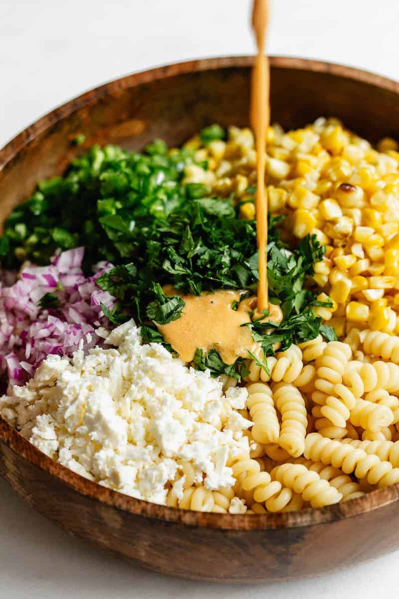 A bowl of creamy elote pasta salad made with rotini pasta, grilled corn, cotija cheese, jalapeños, red onion, cilantro, and a smoky chili-lime dressing inspired by Mexican street corn.