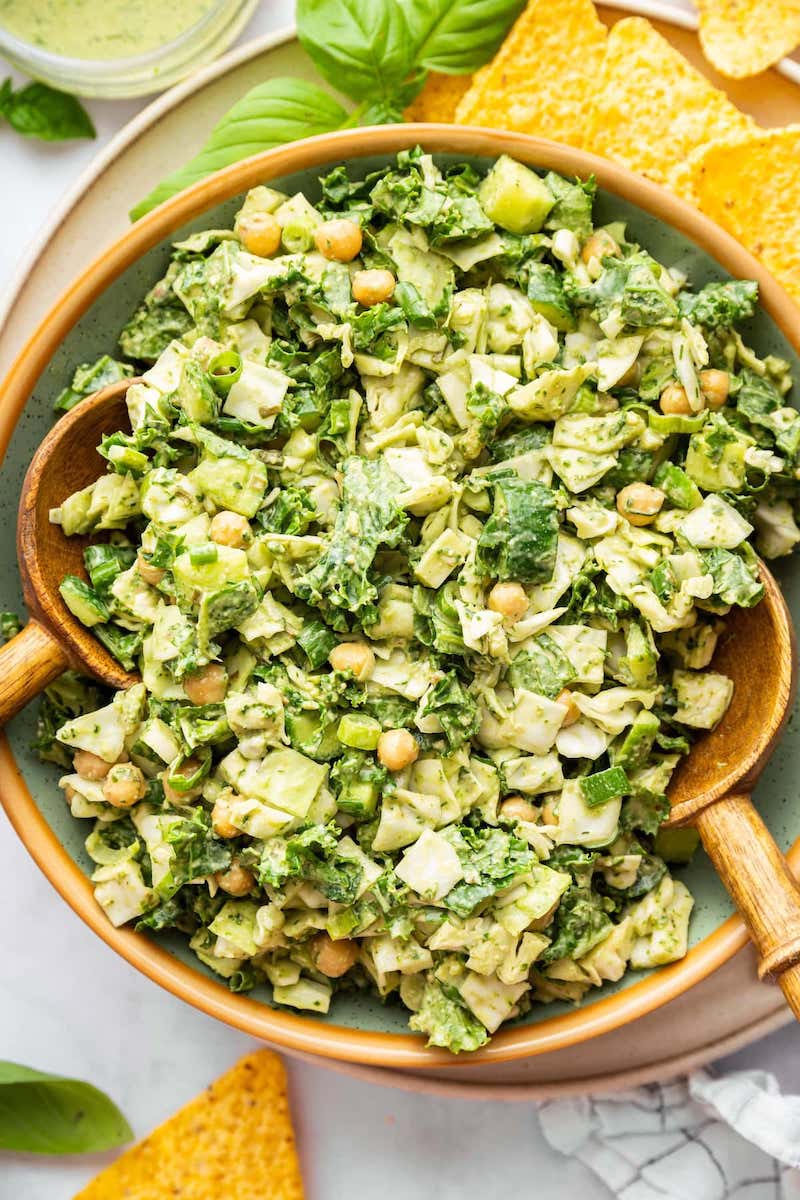 Green Goddess salad with chopped kale, cabbage, cucumber, chickpeas, green onions, and creamy herb dressing in a serving bowl.