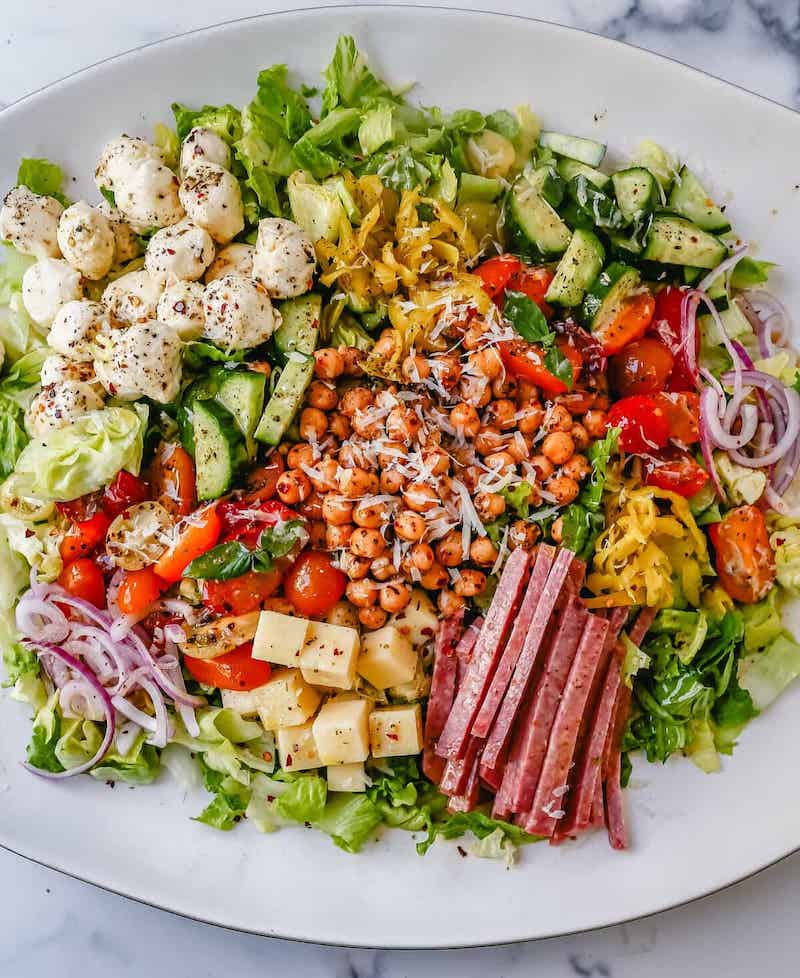 Italian chopped salad with lettuce, salami, mozzarella, provolone, chickpeas, cucumbers, tomatoes, red onion, pepperoncini, and homemade Italian dressing.