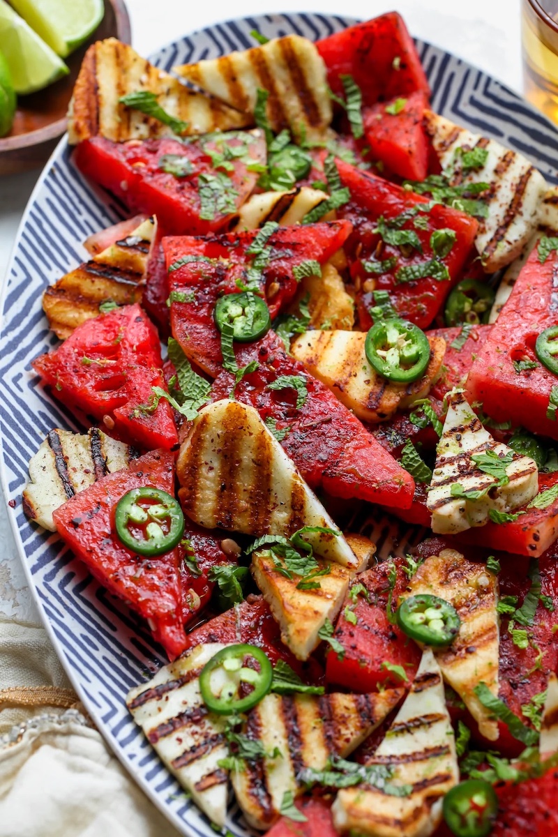 Grilled Halloumi and Watermelon Salad
By Jamie Vespa MS, RD
Grilled Halloumi and Watermelon Salad with jalapeño, mint, and honey-lime dressing. When summer heat calls for something refreshing yet satisfying, this watermelon salad delivers the perfect balance of sweet, spicy, and salty.
Servings:
6
Equipment
Grill pan or outdoor grill
Ingredients
1x
2x
3x
▢2 to 3 Tbsp. avocado oil (or extra-virgin olive oil), divided
▢8 to 9 oz. halloumi cheese, cut into ¼-inch-thick slices and patted dry
▢Kosher salt
▢2 lbs. seedless watermelon (without rinds), sliced into 1-inch-thick slices
▢2 Tbsp. fresh lime juice (plus lime zest for garnish)
▢1 Tbsp. honey
▢1/4 cup chopped fresh mint leaves
▢1 small jalapeño, thinly sliced (if desired, remove seeds and ribs removed for less heat)
▢A few pinches ground sumac (optional)
Save this recipe!
Get this sent to your inbox, plus get new recipes from us every week!
Email *
Save
Instructions
Grill halloumi. Heat 1 Tbsp. avocado or olive oil in a large skillet, grill pan, or outdoor grill over medium-high.
Once hot, arrange halloumi slices in pan and cook for ~2 minutes per side. Transfer to a plate and lightly season with salt. Slice halloumi diagonally into triangular wedges.