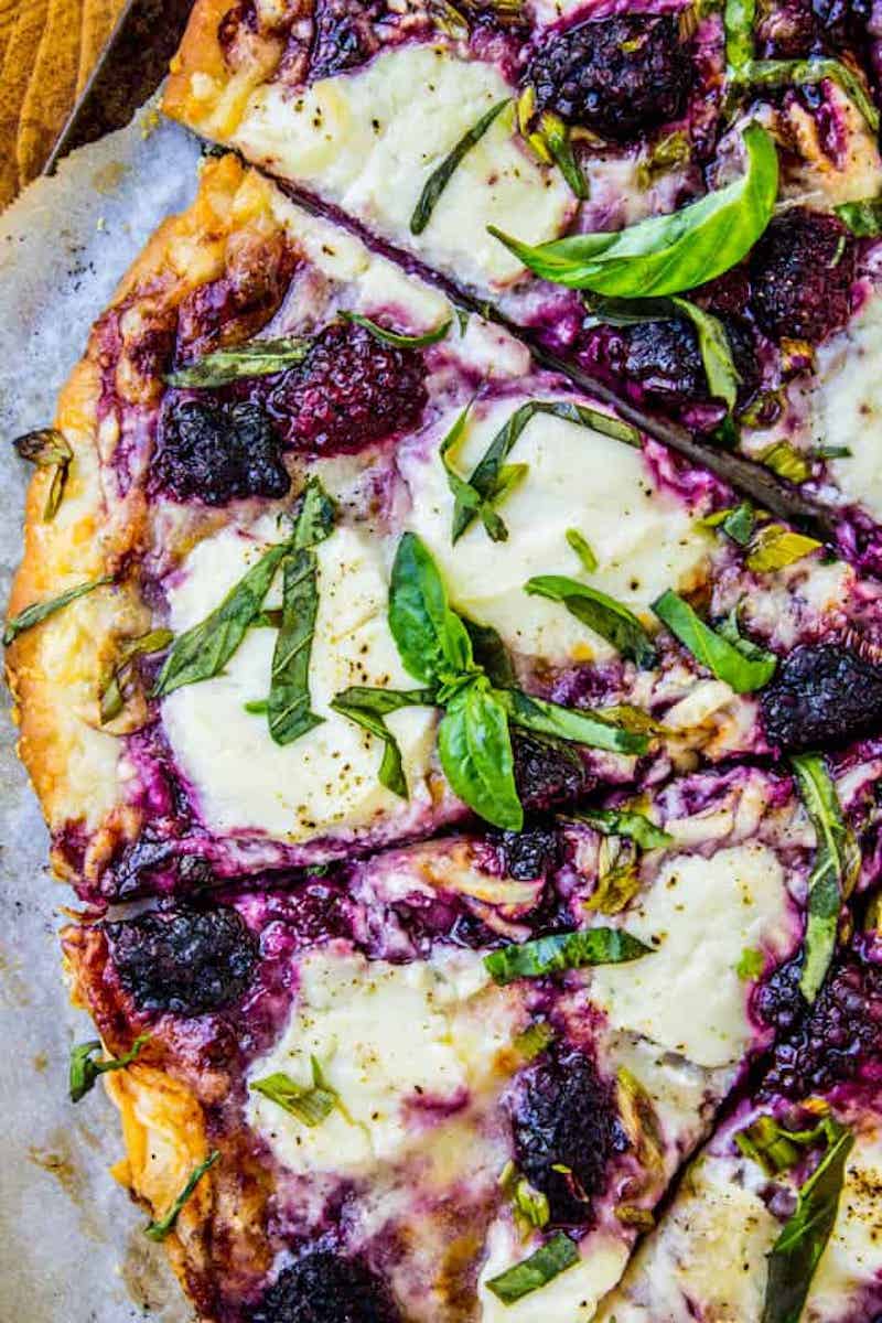 Blackberry ricotta pizza topped with fresh basil and melted cheese.