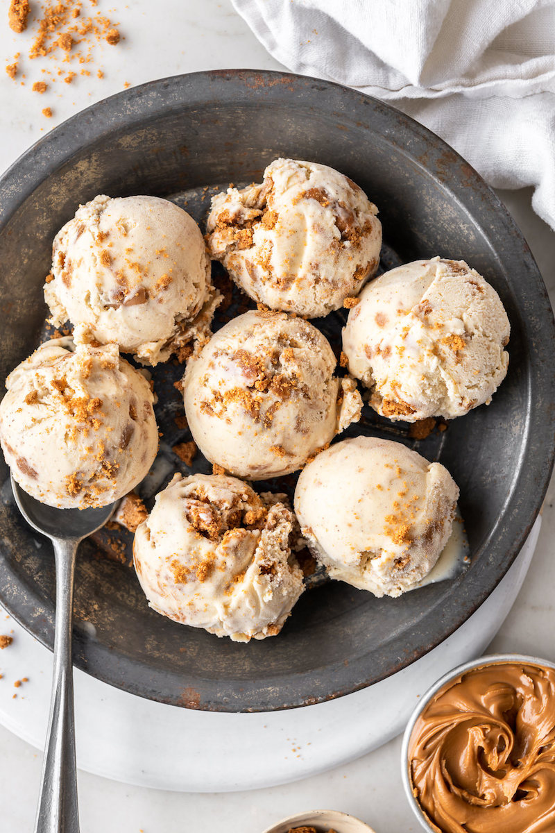 Homemade cookie butter ice cream with swirls of cookie butter and crushed Biscoff cookies served in a metal pan.