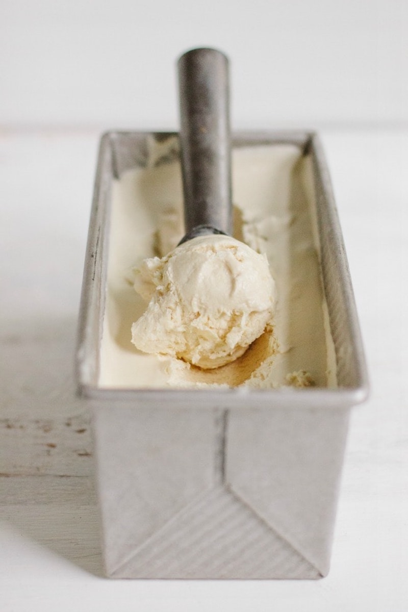 Creamy no-churn Frangelico coffee ice cream in a loaf pan with an ice cream scoop resting on top.