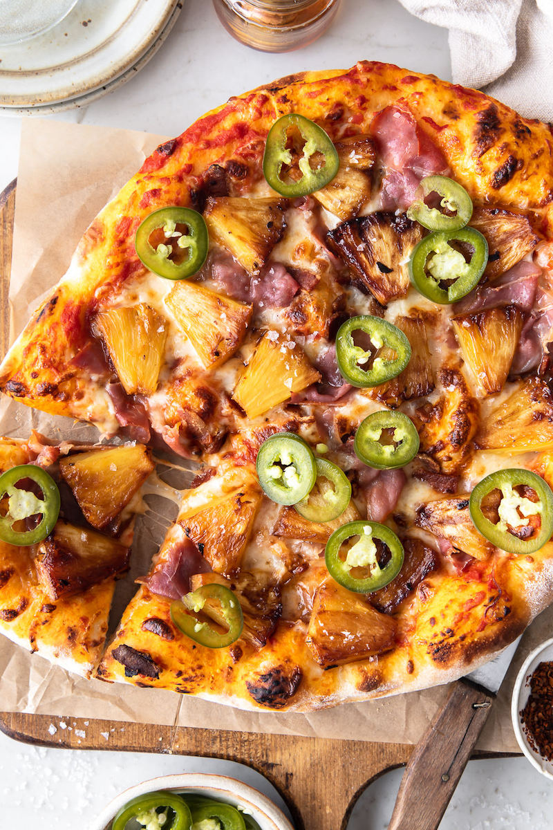 Hawaiian pizza topped with caramelized pineapple, bacon, prosciutto, pickled jalapeños, and mozzarella.