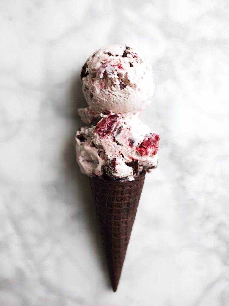 Chocolate waffle cone filled with creamy no-churn cherry chip ice cream with roasted cherries and chocolate chunks.