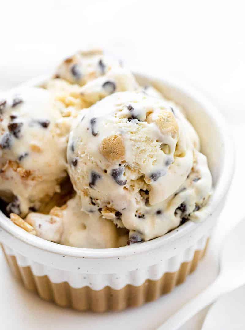 Scoops of creamy no-churn chocolate chip cookie dough ice cream topped with edible cookie dough bites and mini chocolate chips served in a white ramekin.