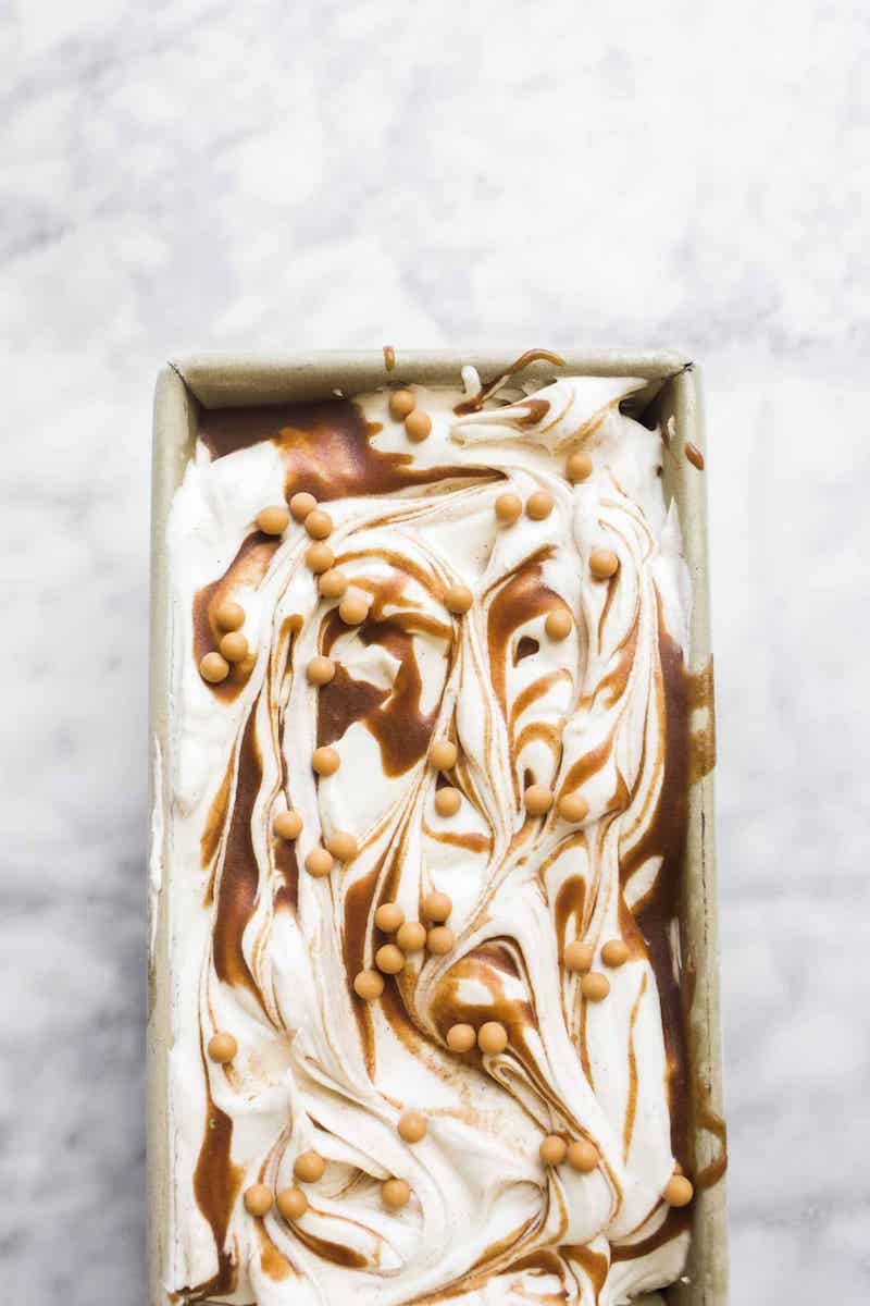 Creamy no-churn cinnamon maple swirl ice cream with ribbons of cinnamon maple sauce in a loaf pan topped with crunchy maple pearls.