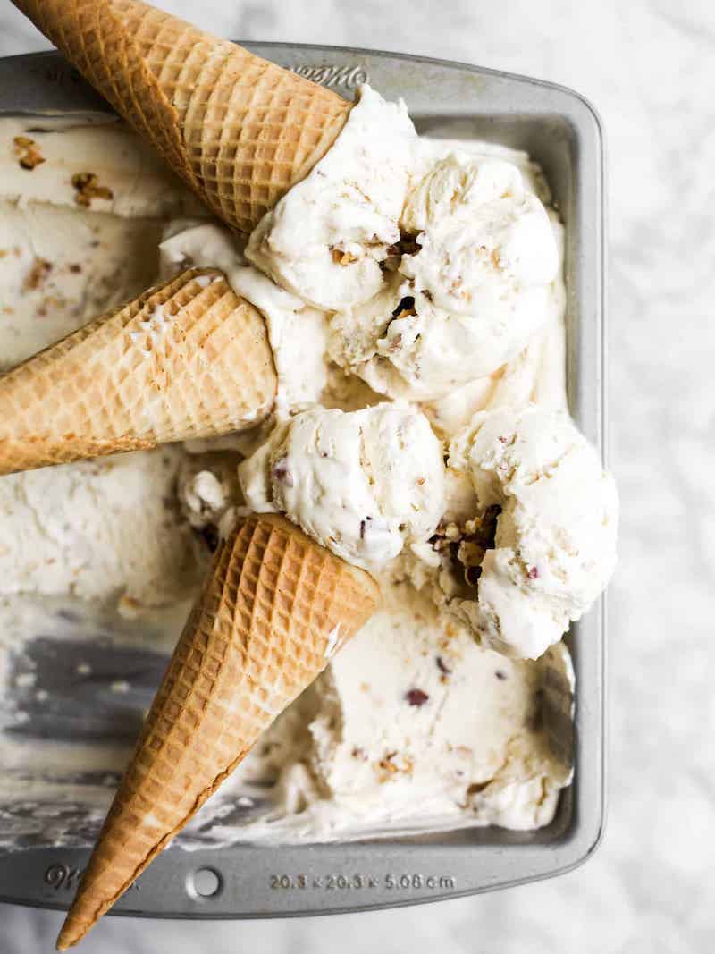 Creamy no-churn honey salted almond ice cream with toasted salted almonds in a loaf pan, served with waffle cones.