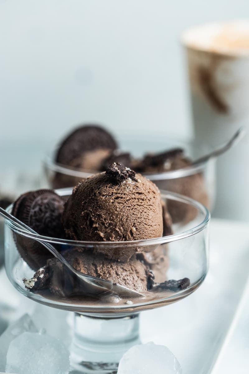 Homemade Oreo ice cream with Oreo cookie pieces served in a glass dessert dish with whole Oreo cookies.