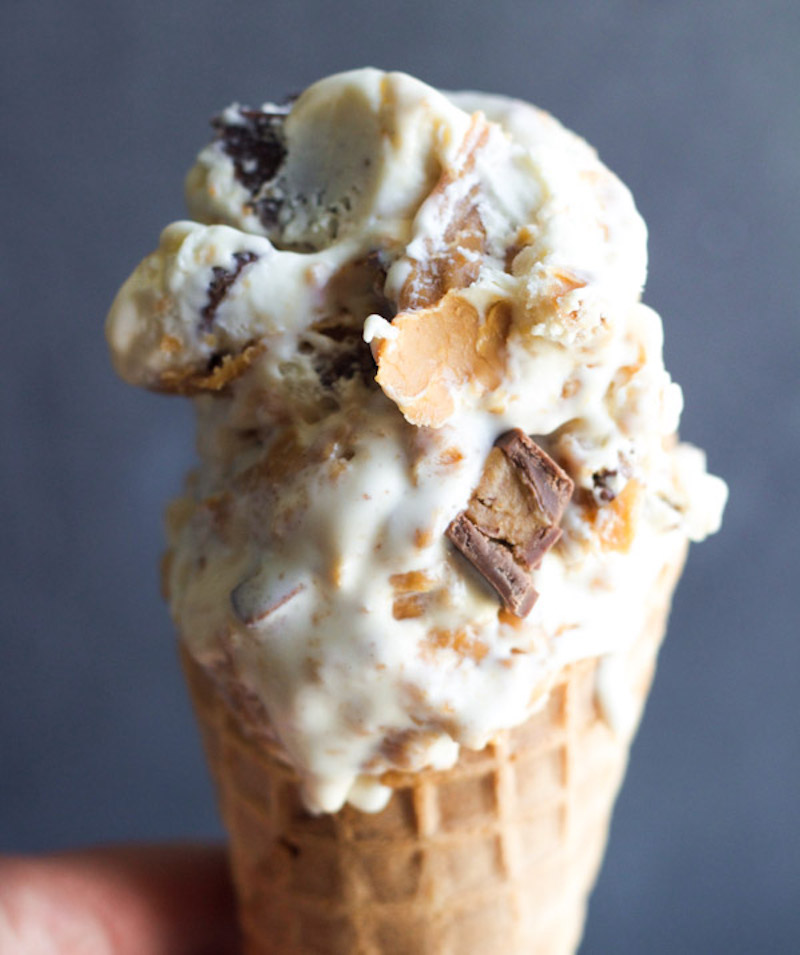 Close-up of homemade peanut butter cup frozen custard in a waffle cone with chopped peanut butter cups and swirls of creamy peanut butter throughout.