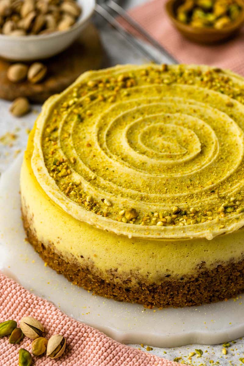 Bright green pistachio cheesecake with a pistachio-graham cracker crust and silky pistachio cheesecake filling made with homemade pistachio paste topped with a smooth pistachio white chocolate ganache and chopped pistachios.