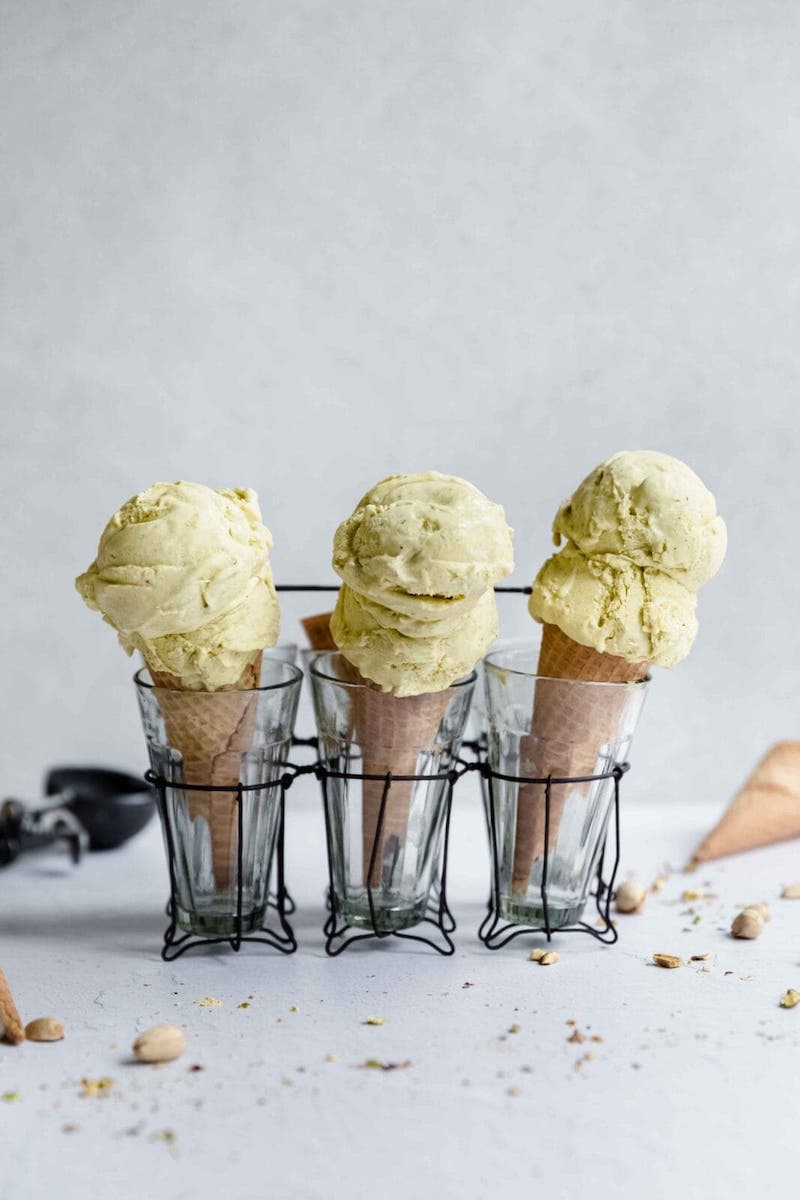 Homemade pistachio ice cream served in waffle cones with scoops of creamy pistachio ice cream made from real pistachios.
