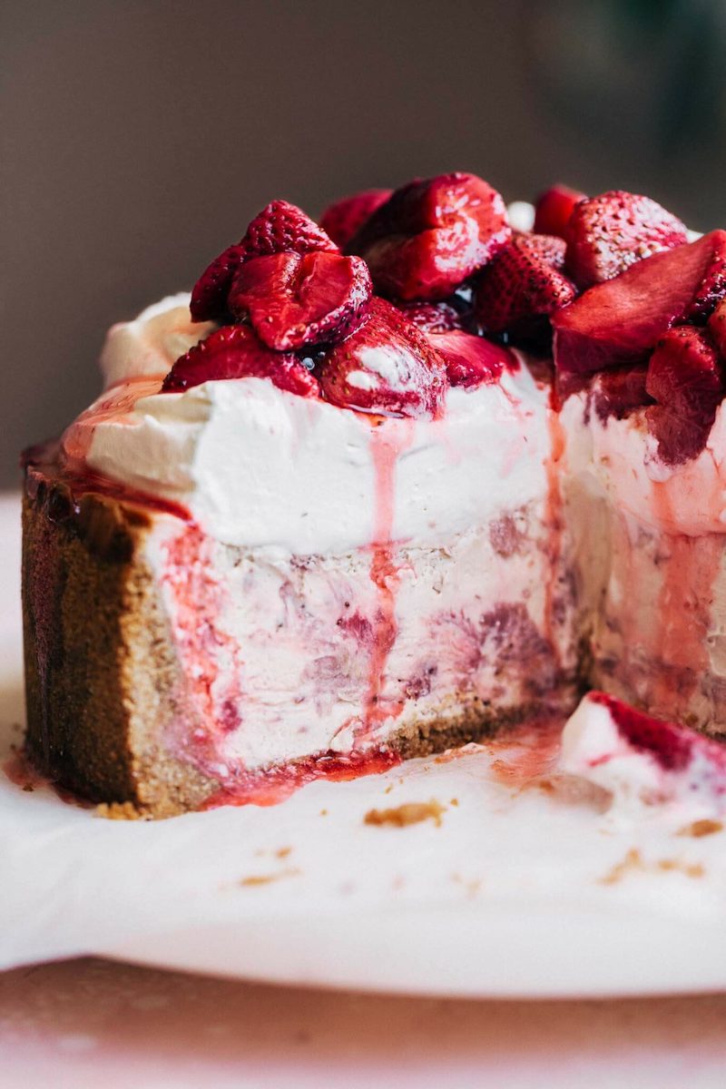 Roasted strawberry cheesecake topped with glossy, macerated strawberries and extra strawberry juices dripping down the sides.