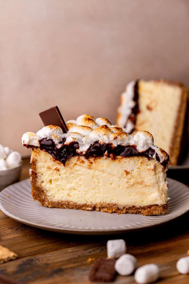 Slice of s'mores cheesecake with chocolate and marshmallow topping.