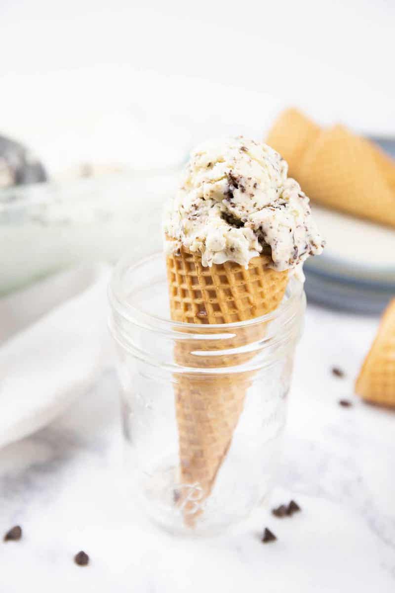 Homemade stracciatella gelato with dark chocolate flakes served in a waffle cone.