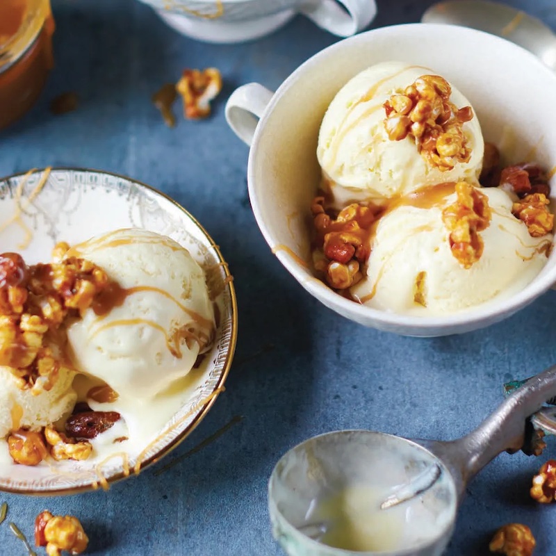 Creamy sweet corn ice cream topped with butterscotch sauce and caramel popcorn served in small dessert bowls.